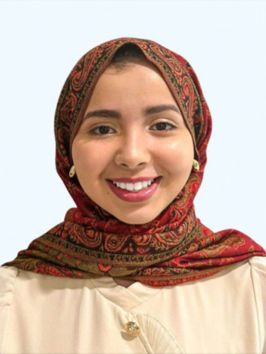 Jehan's headshot features her smiling with a red head wrap and a white button shirt