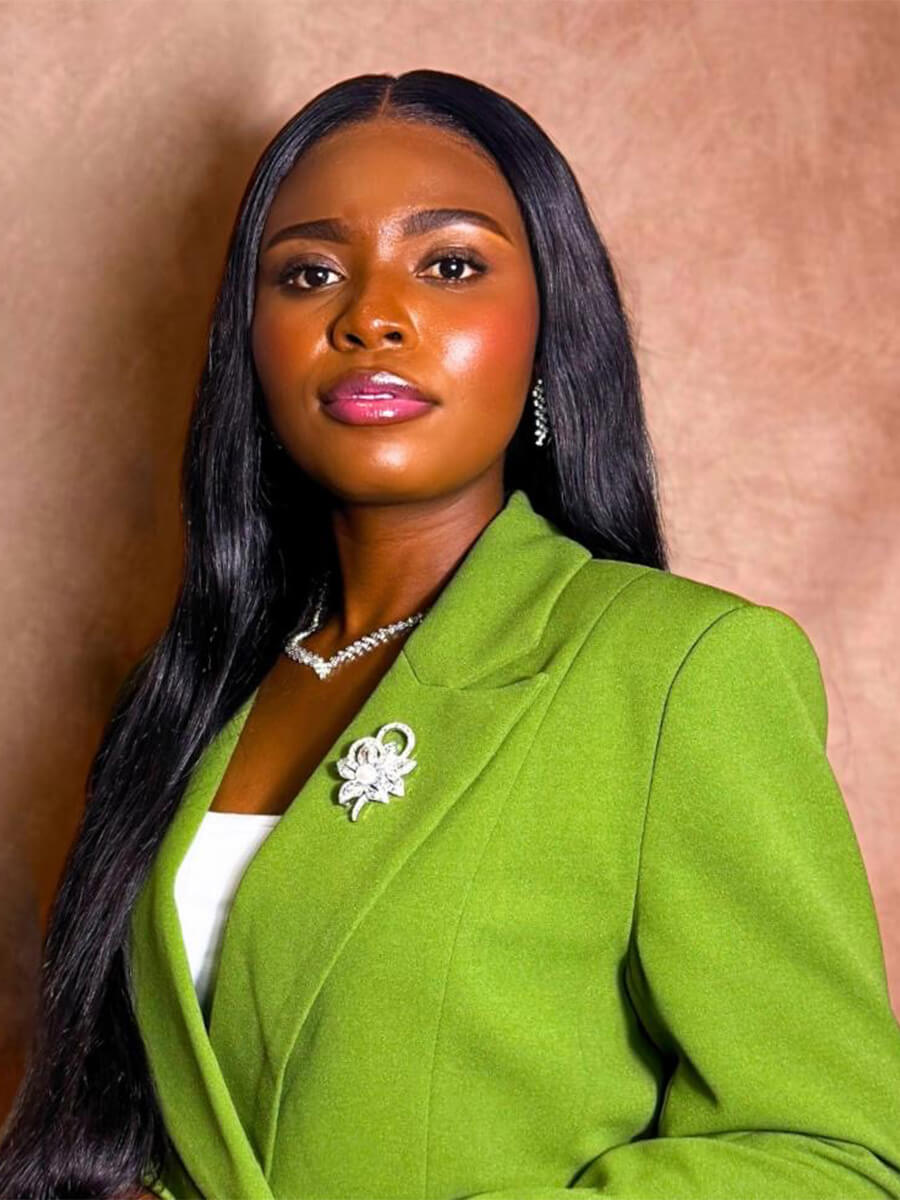Joyce Arthur poses for a headshot wearing a lime green blazer. The background is pink.