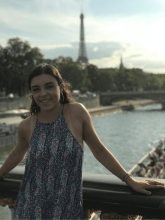 Smiling college student on bridge in front of river and Eiffel Tower