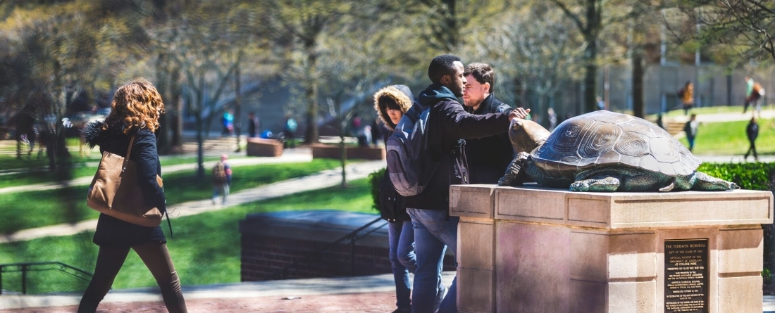 Students walking past Testudo statue on campus