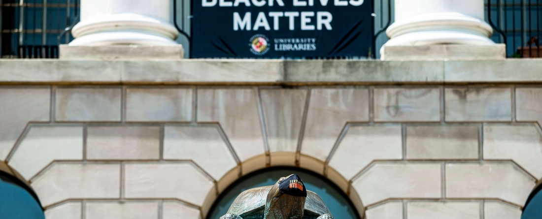 Black Lives Matter sign displayed on McKeldin Library above Testudo statue wearing face mask