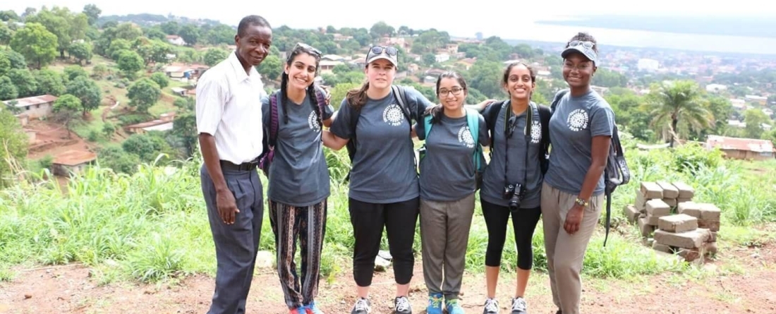 Students from PHBB stand on a hilltop overlooking a lush green valley. 
