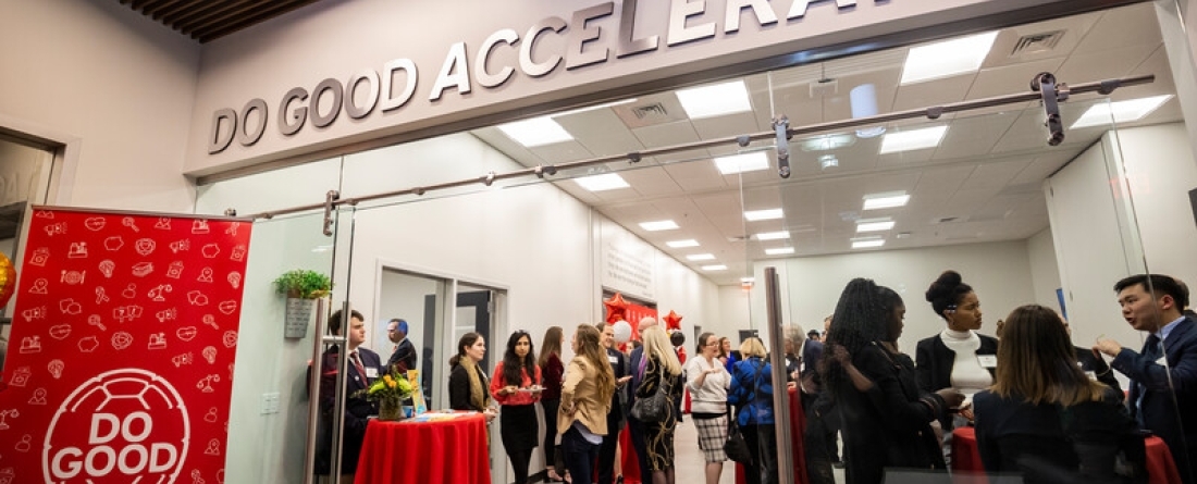 A gathering of people at the Do Good Accelerator, standing around tables and interacting with each other. 