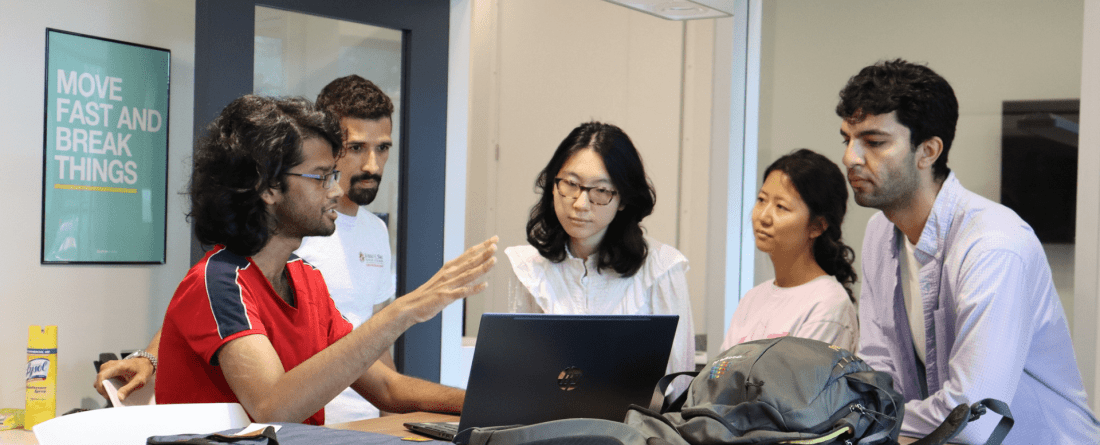 A group of students working on a laptop in the Do Good Accelerator