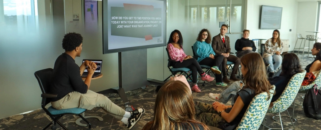 People sitting in chairs in a room with a tv screen