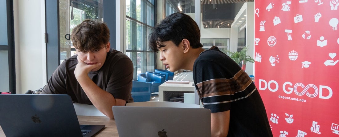 Two students looking intently at a computer screen 